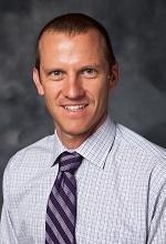 formal portrait image of Greg Rhodes in a dress shirt and tie, smiling