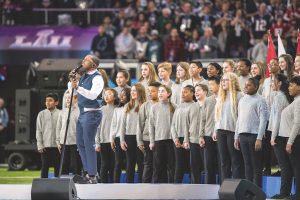 A youth choir performs behind singer Leslie Odom Jr. on the field of U.S. Bank Stadium during the 2018 Super Bowl in Minneapolis.
