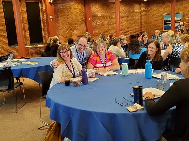 Presenter Stephan Viehweg and session participants smile at the camera while seated at a table