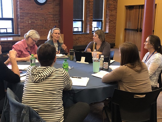 A group of session participants sits around a table talking about an exercise