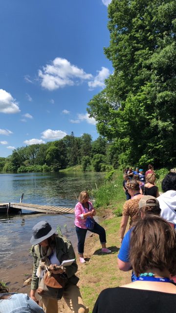 Photo of participants standing on the bank of a pond on a sunny day