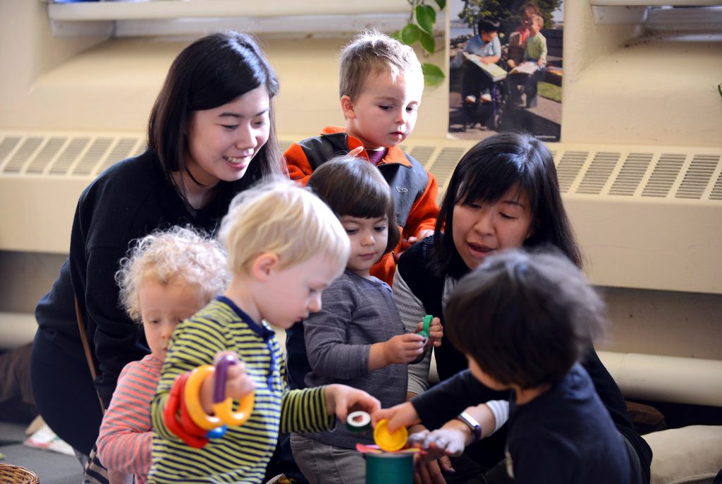 Two teachers and five students play together with toys