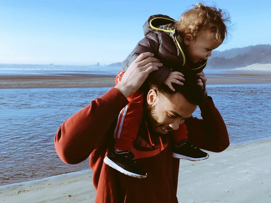 A happy toddler rides on the shoulders of a smiling young man