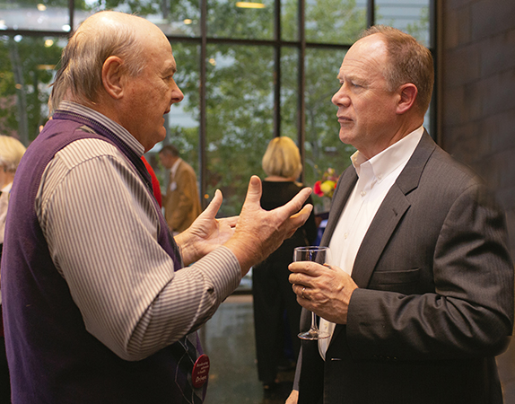 A professor talks to a guest at a University event. 