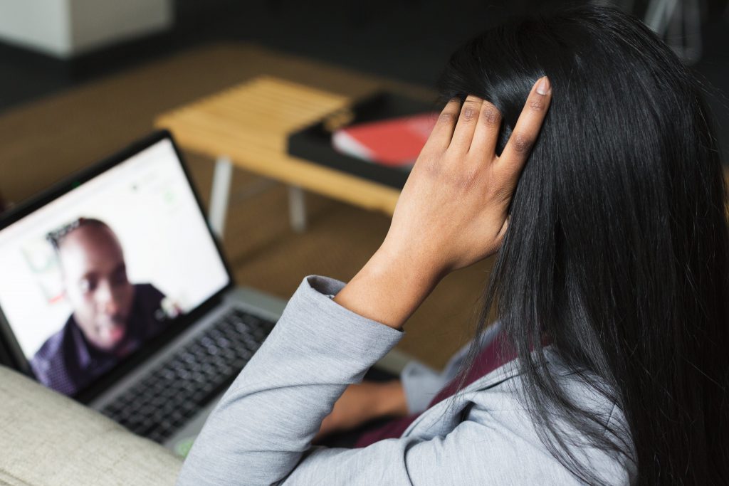 A woman participates in a video conference on her laptop while sitting on a couch